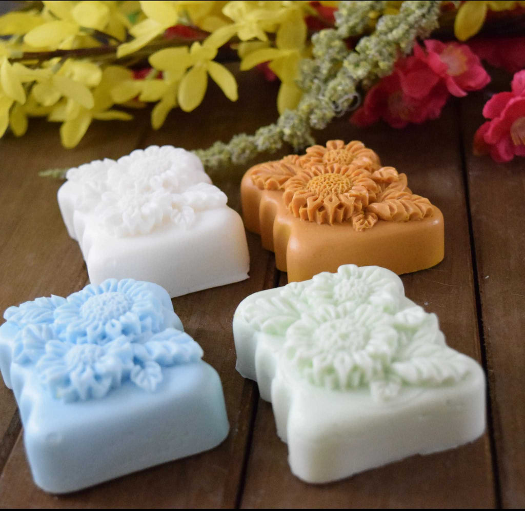 Decorative natural crafted goat milk soap bars in pastel colors with floral designs on wooden surface