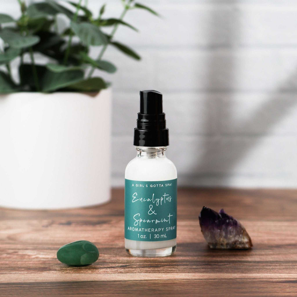 Eucalyptus and Spearmint Aromatherapy Spray bottle with green and purple stones on wooden surface near plant